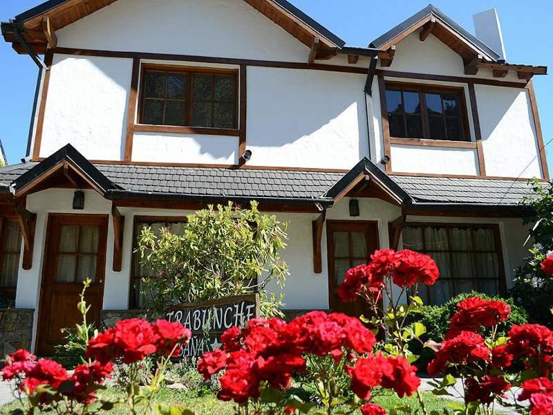 a house with red flowers in front of it at Cabañas Trabunche in San Martín de los Andes