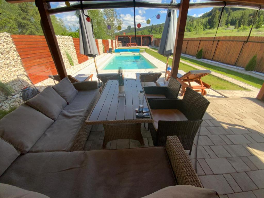 une terrasse avec des canapés, une table et une piscine dans l'établissement Paradise Resort, à Miercurea-Ciuc