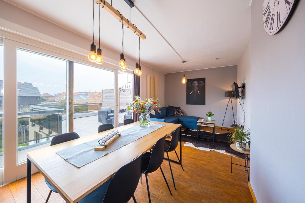 een eetkamer en een woonkamer met een grote tafel en stoelen bij Family Appartement 'MarieO' with Game Room and outdoor facilities in Gistel