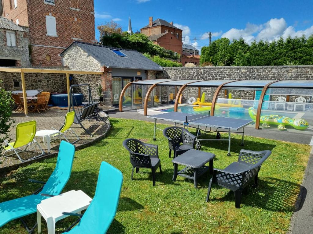 eine Terrasse mit Stühlen, Tischen und einem Pool in der Unterkunft Duplex Swimming Cats in Saint-Hilaire-sur-Helpe