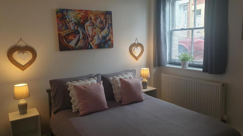 Un dormitorio con una cama con almohadas y una pintura en Beautiful Apartment 2 mins To The Beach, en St. Leonards