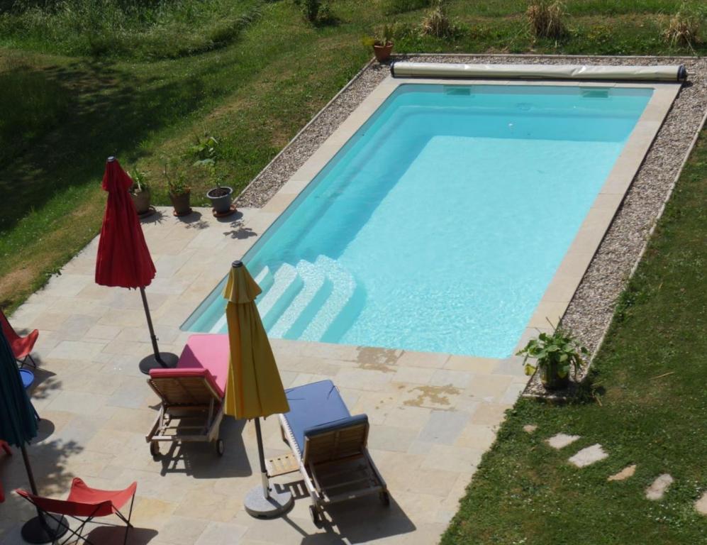 a swimming pool with chairs and umbrellas next to it at Domaine de Saint Loth' in Saint-Lothain