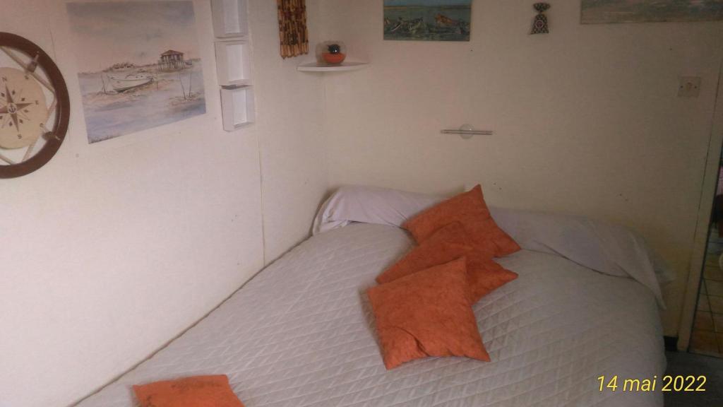 um quarto com uma cama com almofadas laranja em petit chez soi dans mon petit chez moi em Biganos