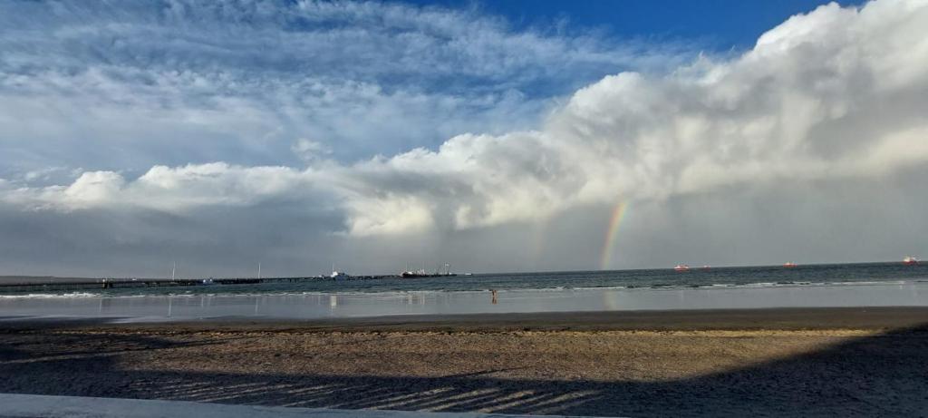 a rainbow on a beach with the ocean and the sky at AQUAMARINA 4 in Puerto Madryn