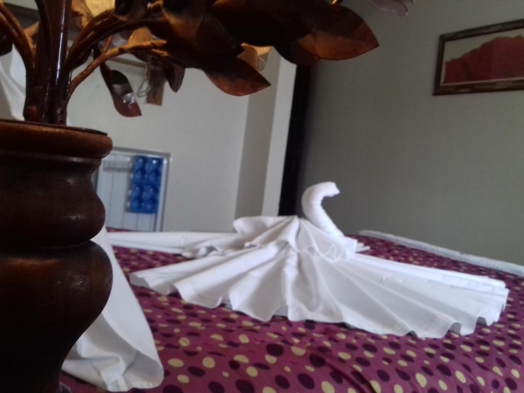 Una cama con sábanas blancas y un jarrón. en Thetis Hotel Pousada, en Arraial do Cabo