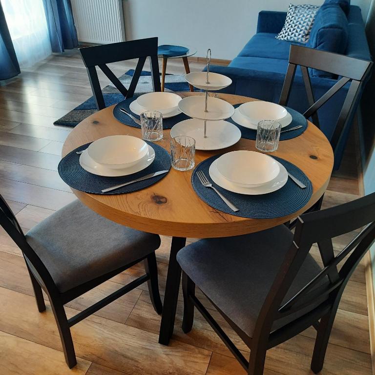 a wooden table with plates and glasses on it at Niebieski - Mala Apartamenty in Rumia