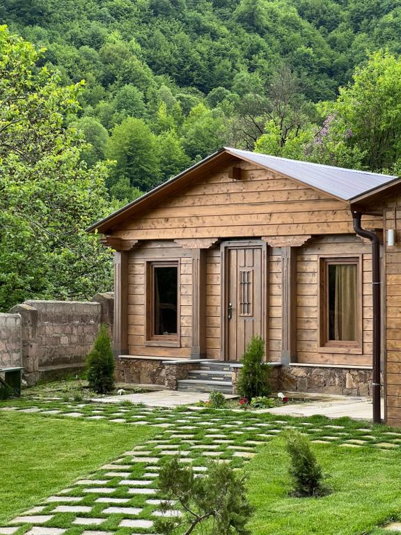 una pequeña casa de madera con un camino de piedra delante de ella en Balkonchik GuestHouse, en Dilijan