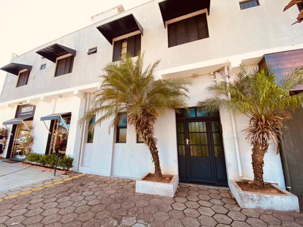 a building with two palm trees in front of it at Anexo - Hospedagens Imigrantes in São Pedro