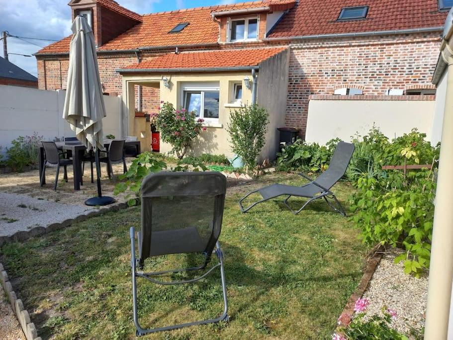 a yard with a table and an umbrella and chairs at maison chaleureuse solognote mitoyenne in La Ferté-Saint-Aubin