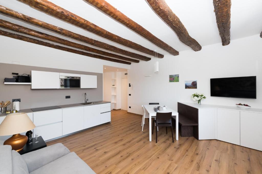 eine Küche und ein Wohnzimmer mit weißen Schränken und einem Tisch in der Unterkunft Appartamento Terme in Levico Terme