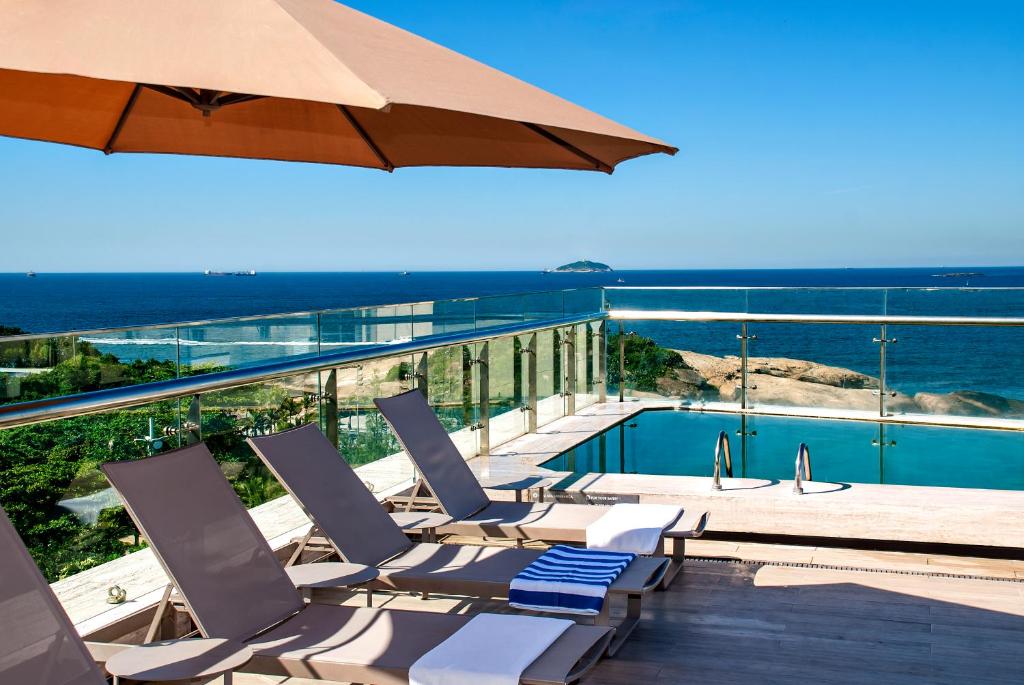 a pool with chairs and an umbrella on a balcony at Arena Ipanema Hotel in Rio de Janeiro