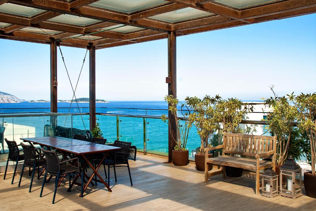 een patio met een tafel en stoelen en de oceaan bij Arena Ipanema Hotel in Rio de Janeiro