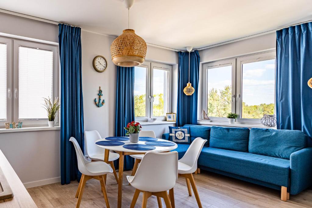 sala de estar con sofá azul, mesa y sillas en Apartamenty Marynarskie, en Debina