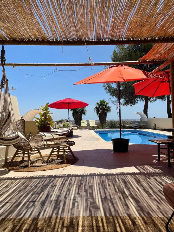 un patio con mesas, sombrillas y una piscina en Casa Romeo y Julieta, en Castro Marim