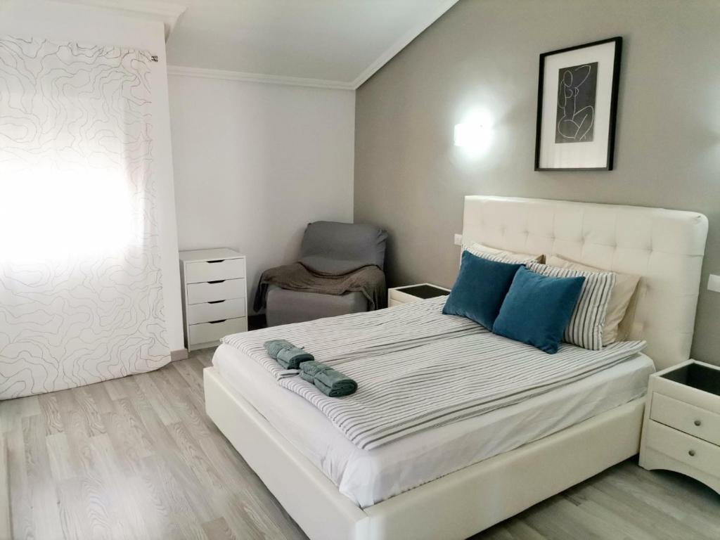 a bedroom with a large white bed with blue pillows at Sunshine Beach Apartments in Adeje