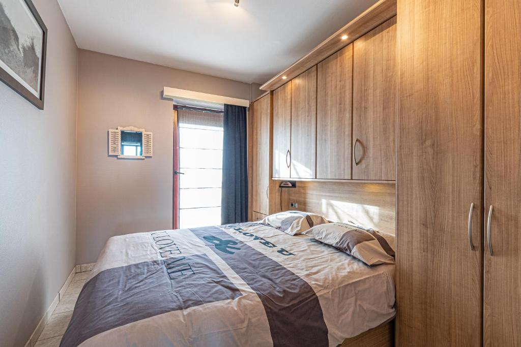 a bedroom with a bed and wooden cabinets at Appartement Blankenberge Zeedijk aan de Pier in Blankenberge