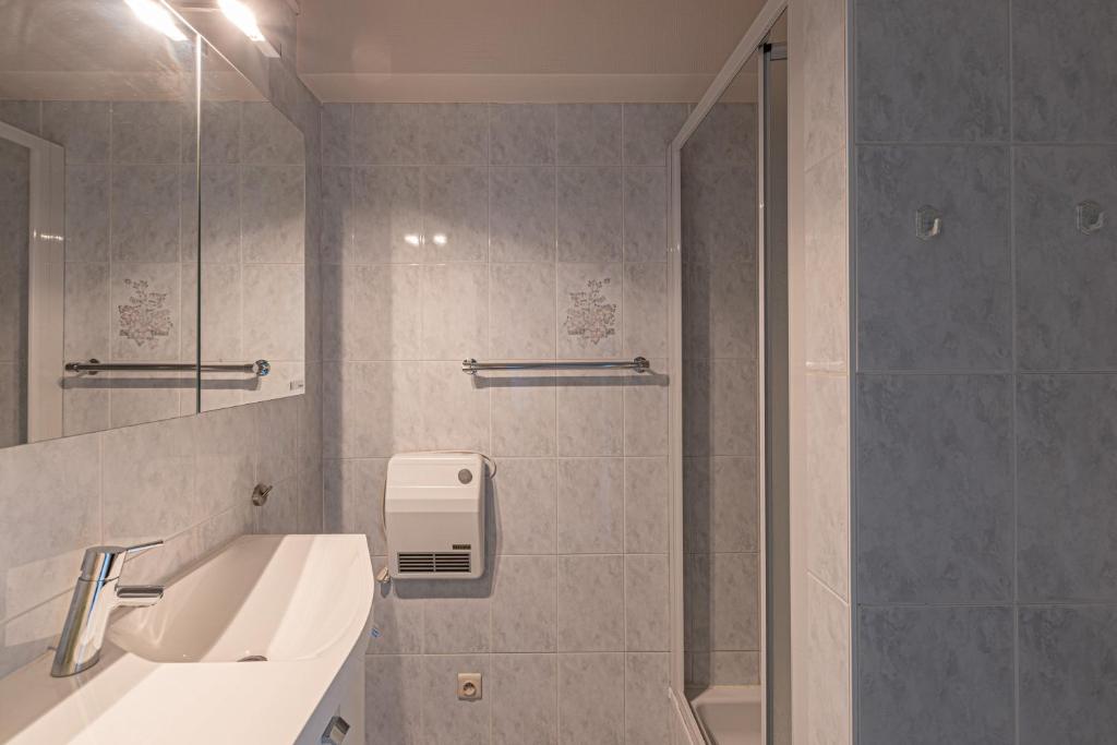 a bathroom with a shower and a sink and a mirror at Appartement Blankenberge Zeedijk aan de Pier in Blankenberge