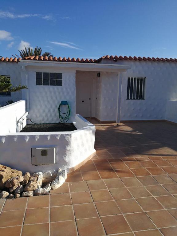 a backyard with a white house and a patio at Casa Kiara in Costa Calma