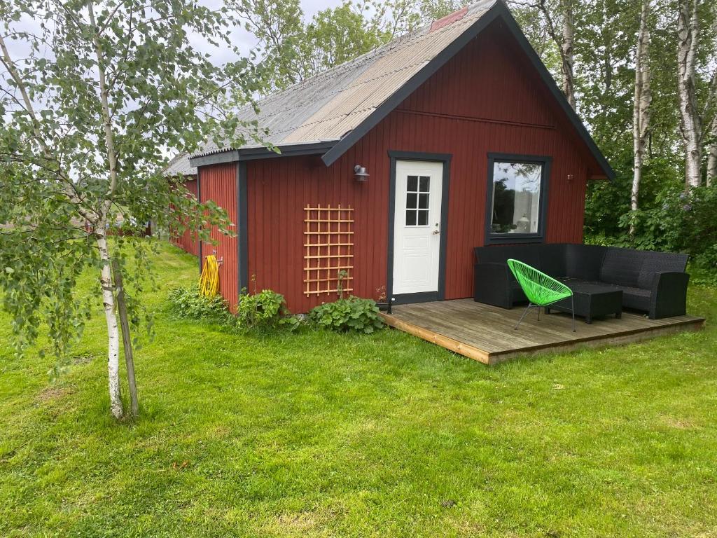 un hangar rouge avec une terrasse et un fauteuil vert dans l'établissement Lilla Sandslätt, à Åhus