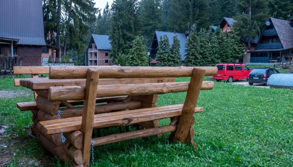 a wooden bench sitting in the grass in a yard at Alpin Apartments Vlašić in Vlasic