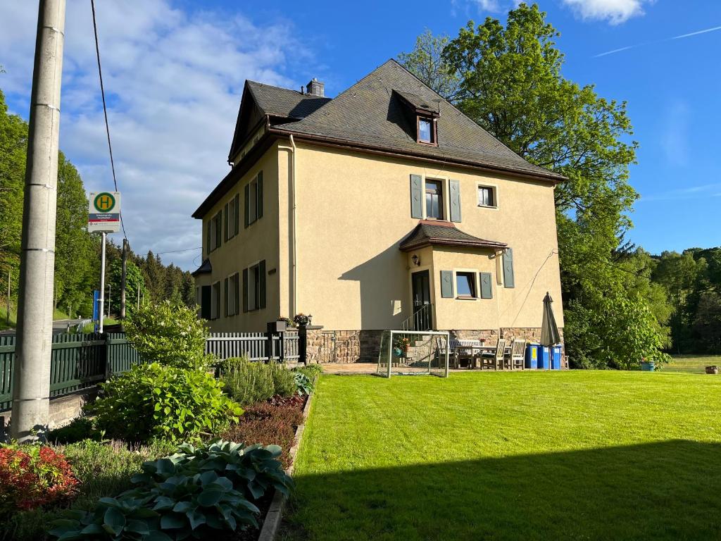 une grande maison avec une pelouse verte en face de celle-ci dans l'établissement Ferienwohnung Schmalzgrube, à Jöhstadt