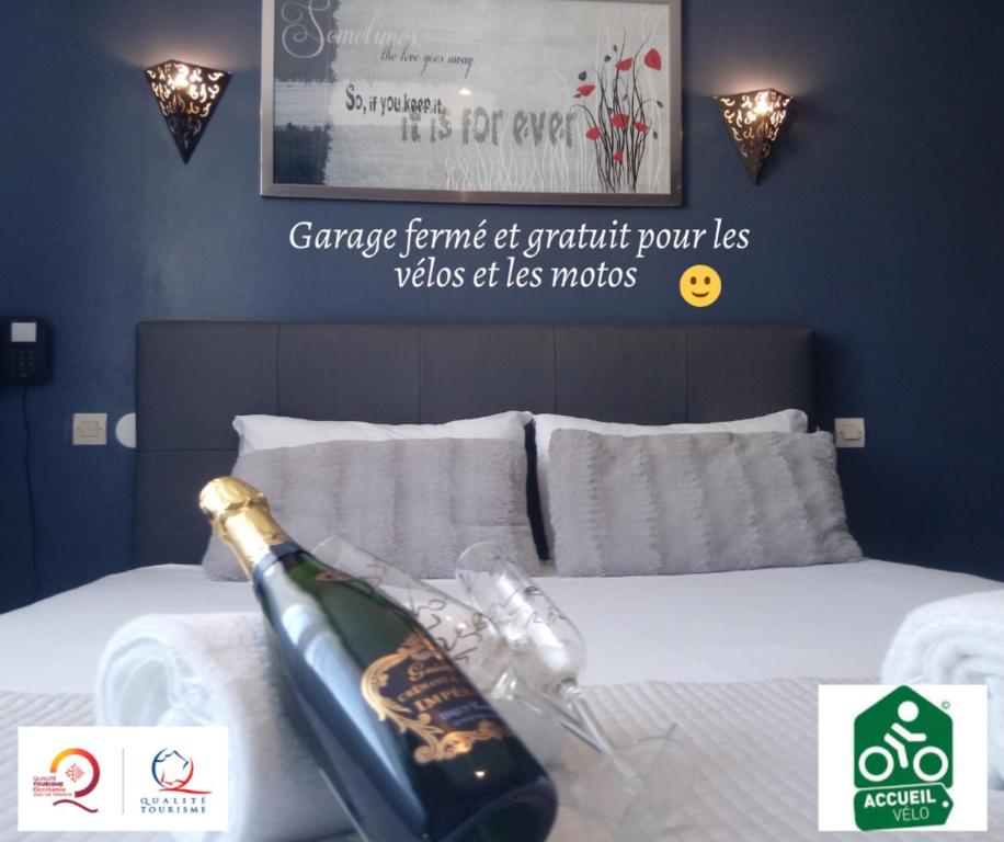 Una botella de champán encima de la cama. en Hotel Astoria en Carcassonne