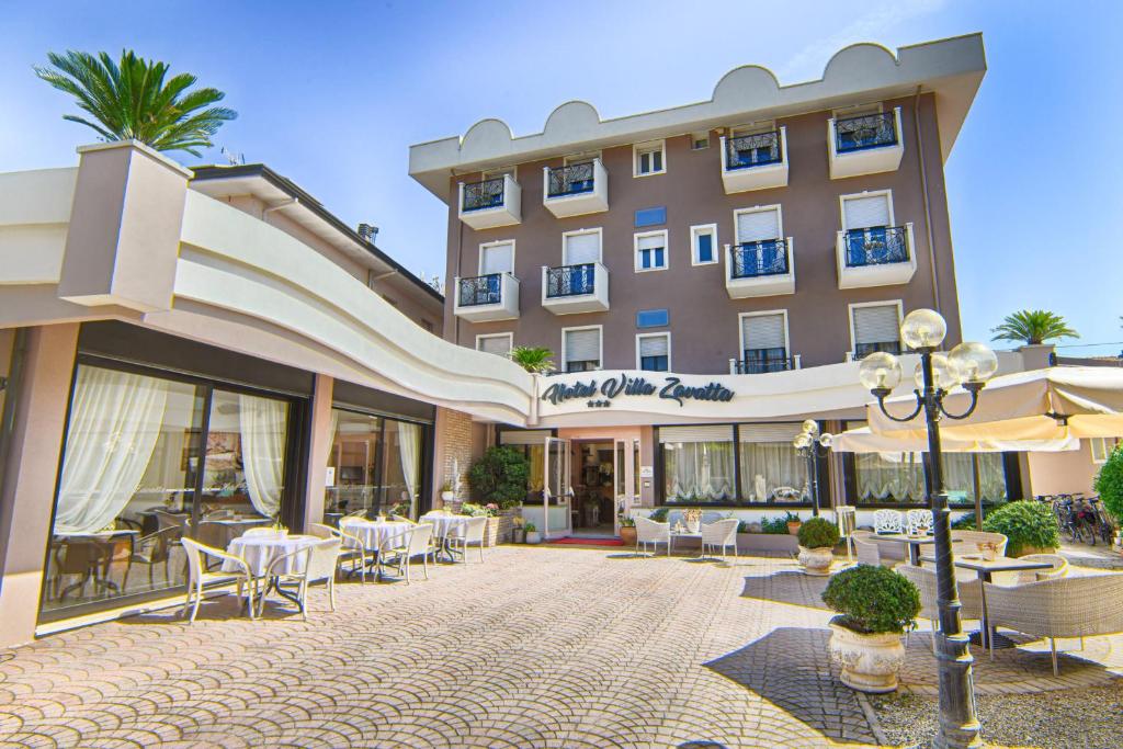 un hotel con mesas y sillas en un patio en Villa Zavatta "B&B - Rooms & Apartments", en Bellaria-Igea Marina