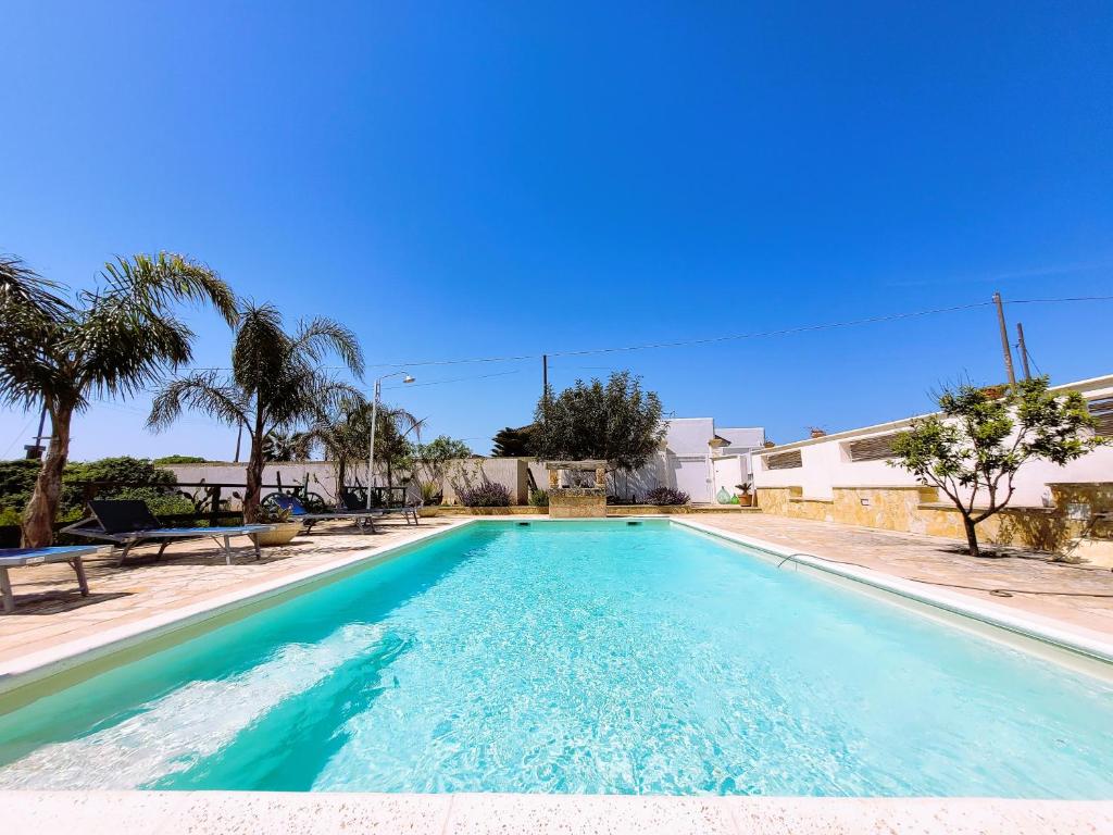 una piscina con acqua blu e palme di Le cicale a Tiggiano