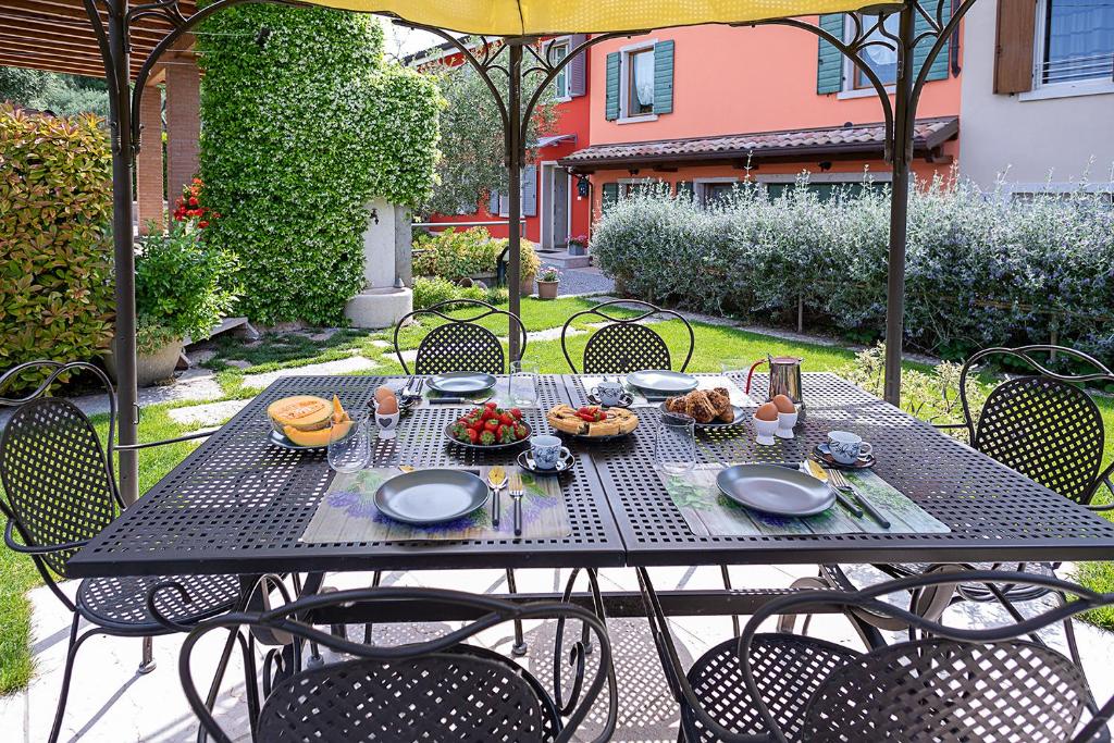 a picnic table with food on it in a garden at RUSTICO PETRA - Regarda Travel in Bardolino