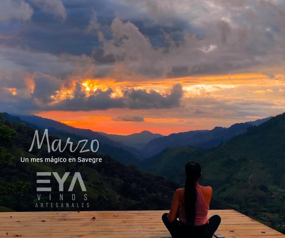 Eine Frau, die auf einem Felsvorsprung sitzt und den Sonnenuntergang beobachtet. in der Unterkunft EYA Ecolodge in San Isidro