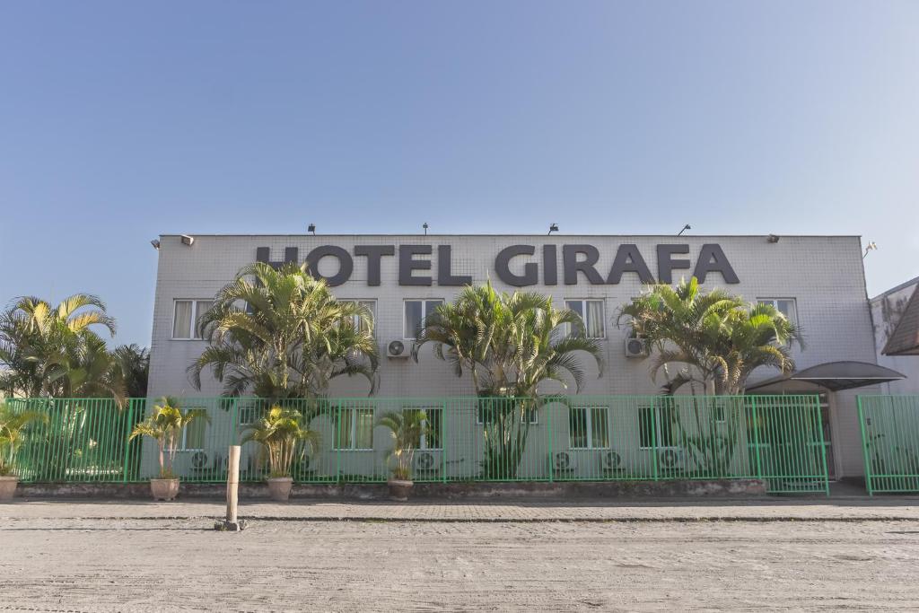 a hotel with palm trees in front of a building at Hotel Girafa in Itatiaia