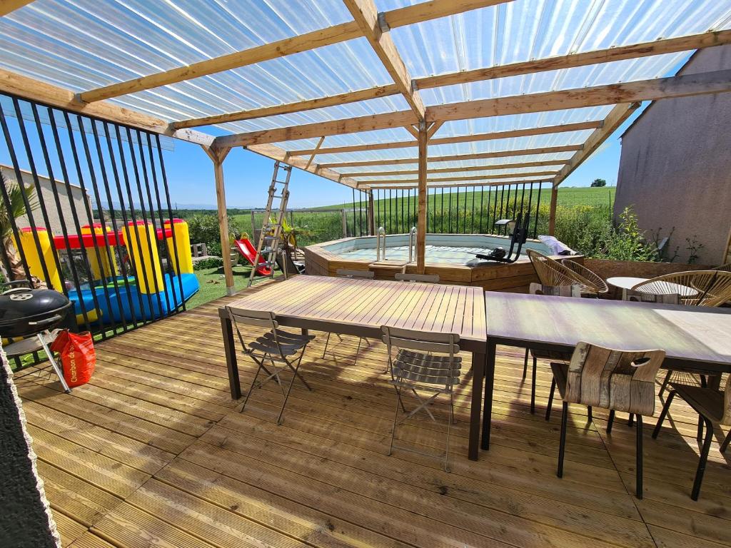 una terraza con mesa, sillas y bañera de hidromasaje. en Villa avec piscine sans vis-à-vis, en Caux-et-Sauzens