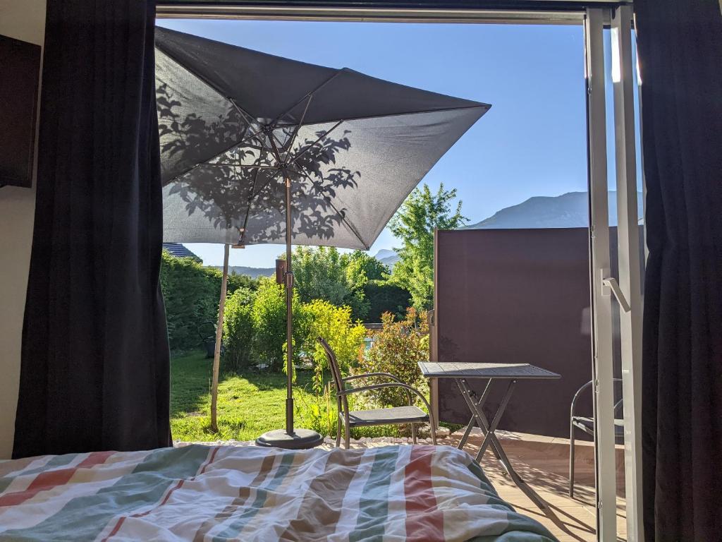 a patio with a table and an umbrella in front of a window at Rez de jardin indépendant in Gap