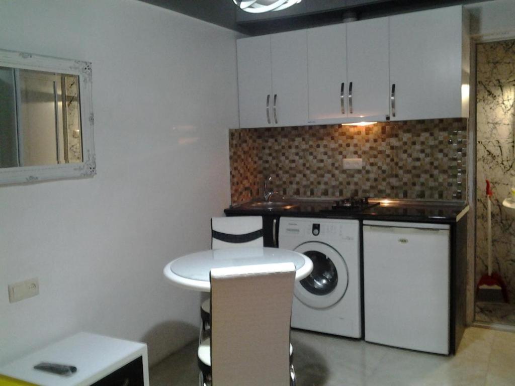 een keuken met een tafel en een wasmachine bij Anna's Apartment in Batoemi