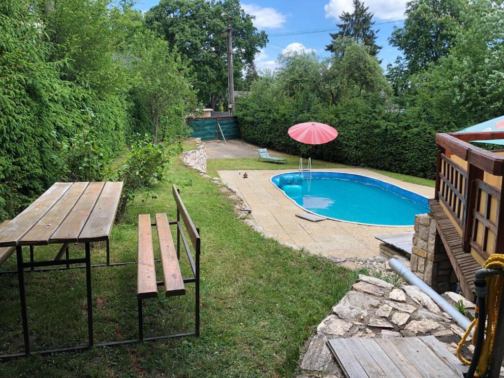 uma mesa de piquenique e um guarda-sol ao lado de uma piscina em Chata u Samka em Rimavská Sobota