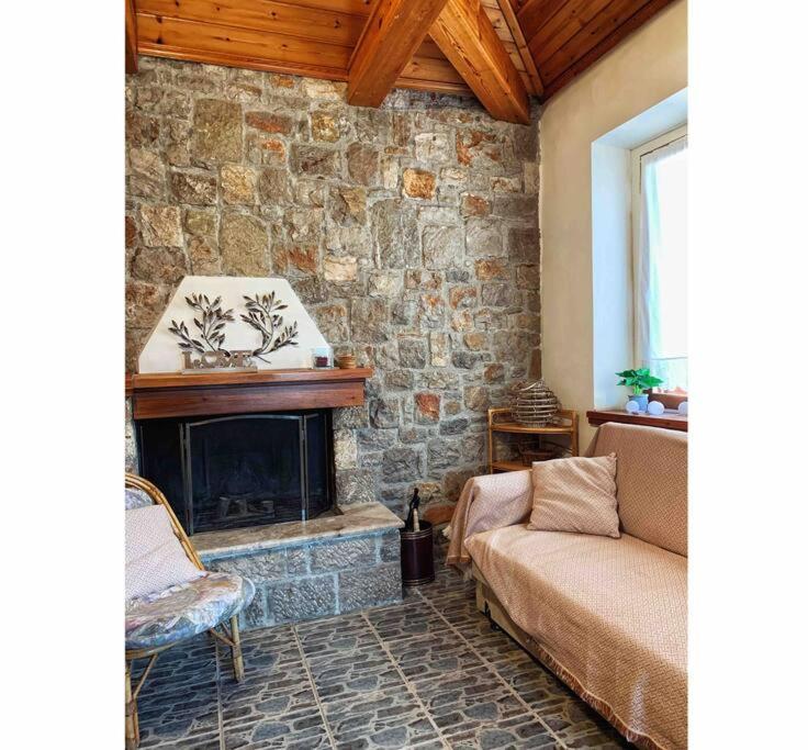 a living room with a stone fireplace and a couch at Aspa's Traditional House in Didyma