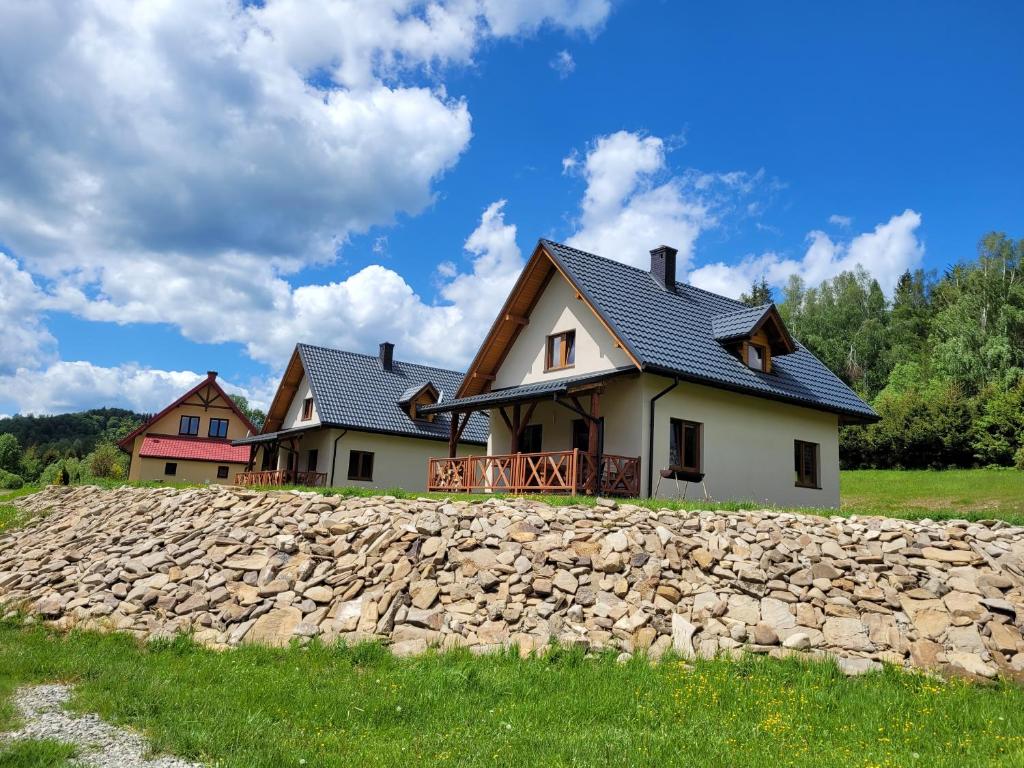 ein Haus mit einer Steinmauer vor einem Haus in der Unterkunft Domki u Gretka in Lutowiska