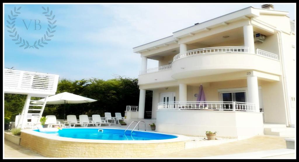 a large white house with a swimming pool in front of it at Villa Bella By The Sea - Heated Pool, Jacuzzi, Sauna in Kožino