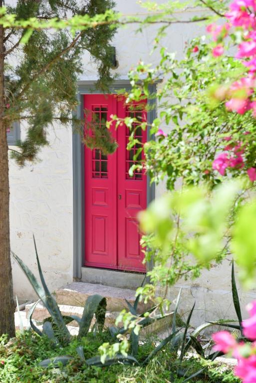 a red door on a house with pink flowers at Douskos Porta Rossa in Hydra