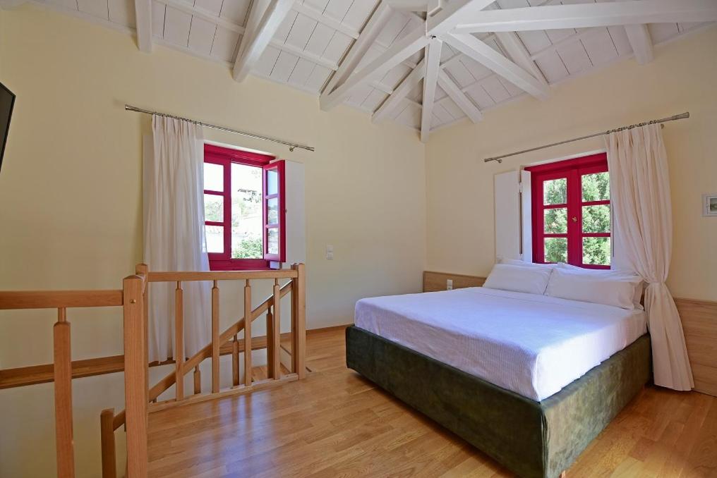 Un dormitorio con una cama y dos ventanas. en Douskos Porta Rossa, en Hydra