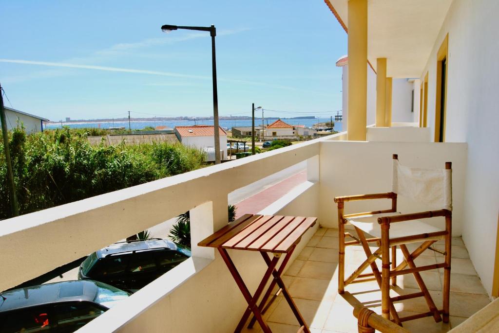 uma varanda com uma mesa, uma cadeira e um carro em Carlos House - Baleal beach, Sunny balcony, Shared pool no Baleal