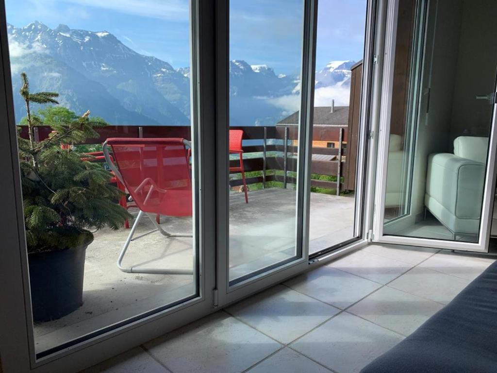 d'un balcon avec une chaise rouge et une vue sur la montagne. dans l'établissement Revier Silberwiidä-Galerie, à Braunwald