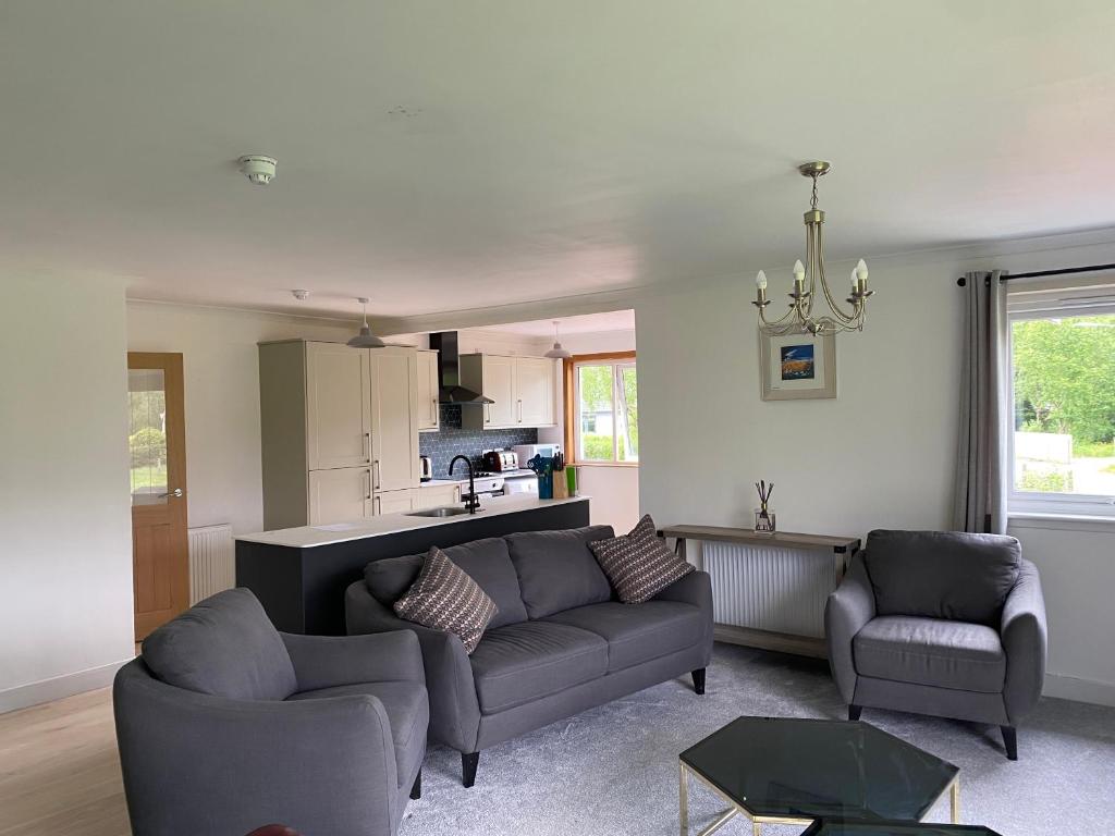 a living room with two couches and a kitchen at Lyn leven cottages in Ballachulish