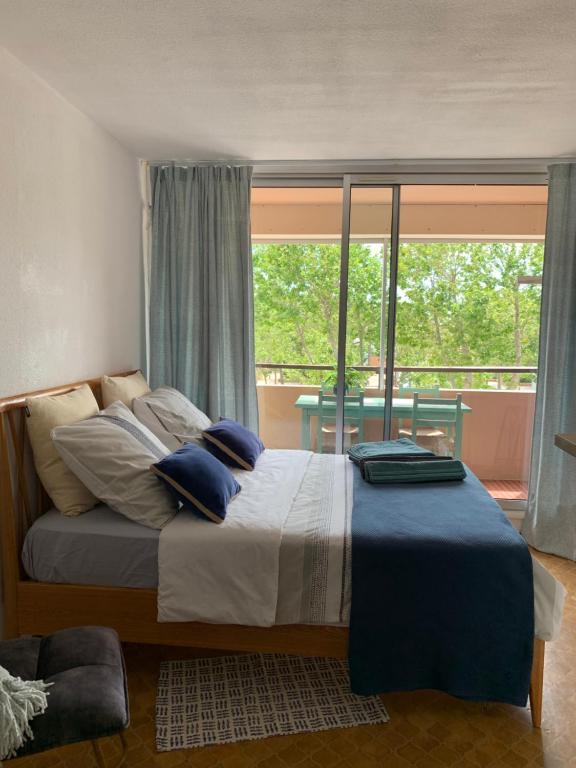 a bedroom with a bed with blue pillows and a window at Studio Les Régates à Gruissan in Gruissan