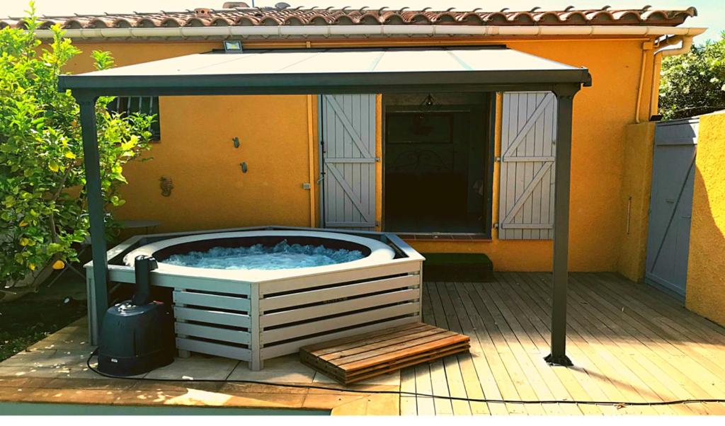 bañera de hidromasaje en un cenador en una terraza en SUITE SPA PRIVATIF extérieur 66 Perpignan Nord, en Pia