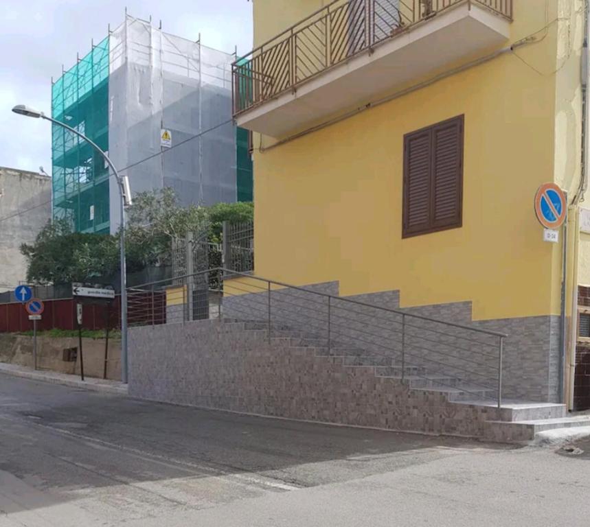 ein gelbes Gebäude mit einer Treppe neben einer Straße in der Unterkunft casa vacanze Rosanna in Balestrate