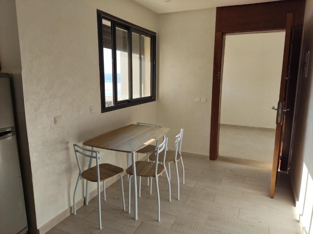 a table and chairs in a room with a window at Nice appa in Kenitra