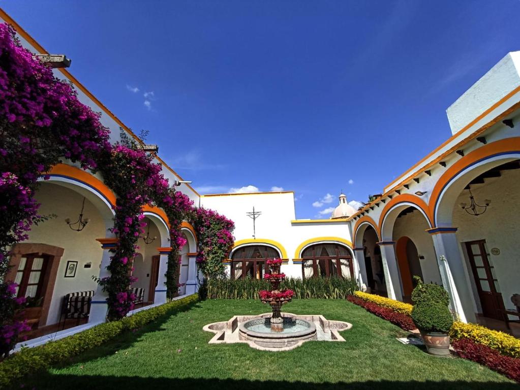 un patio de un edificio con una fuente y flores en Posada del Virrey, en Tequisquiapan