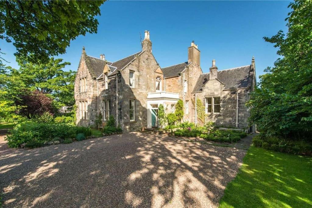 una antigua casa de piedra con un gran patio en Luxury 5-bed Villa - Winfields House, en Prestonpans