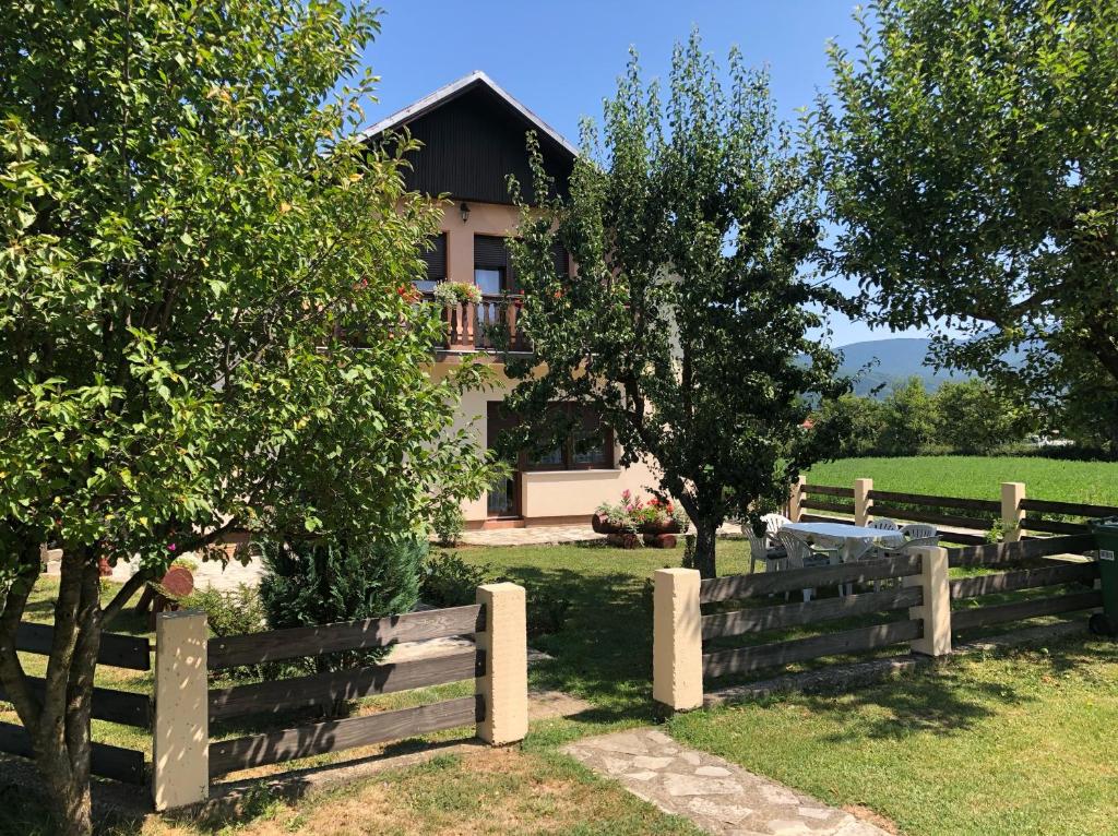 una casa detrás de una valla de madera con árboles y una valla en Apartment Arya, en Korenica